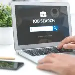 Seseorang sedang membuka laptop dengan tampilan layar "Job Search".