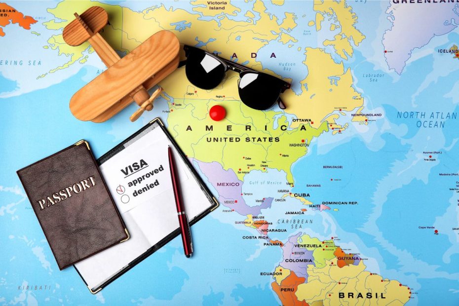 Peta dunia dengan buku paspor, visa, kacamata, dan mainan pesawat di atasnya.